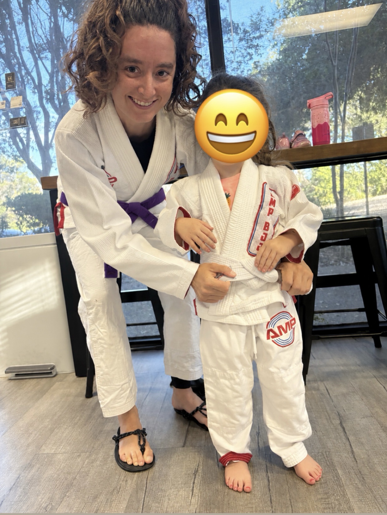 Zoe in her gi, tying a student's belt